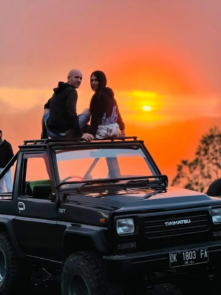 Couple sitting on a 4WD Daihatsu Taft jeep watching the Mount Batur sunrise in Kintamani