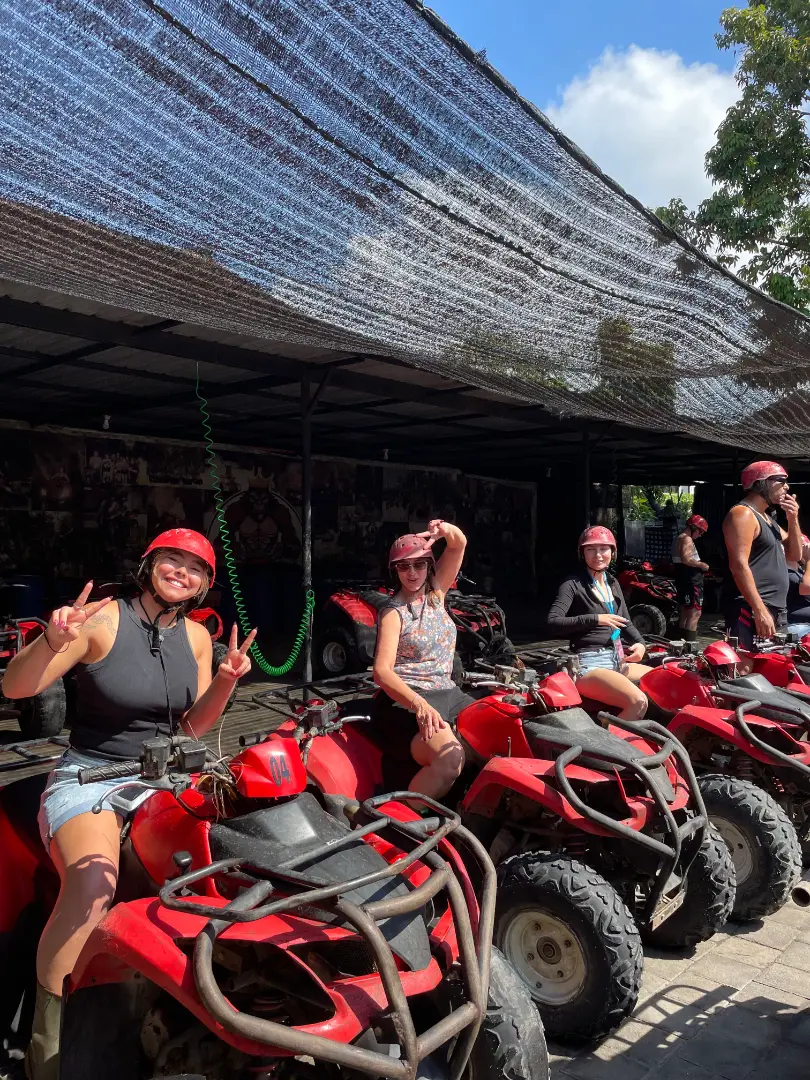 Group of women smiling and posing on red ATVs before jungle ride in Ubud